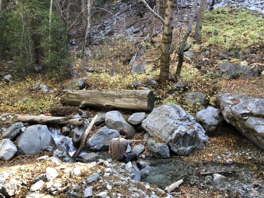 Nick Raya putting on boots by the stream