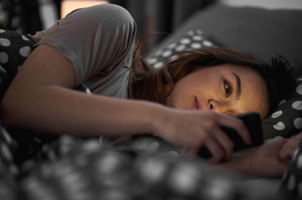 A teenage girl staying up into the night on her smartphone. 