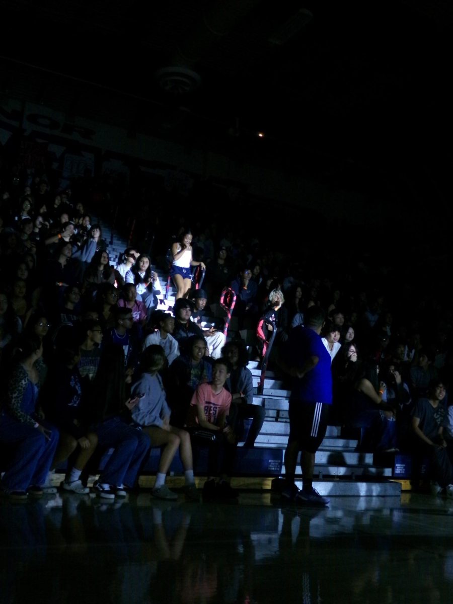 A member of Song walks through the bleachers during their pep rally performance